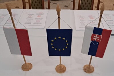 na stole stoją w formie proporców małe flagi polski unii europejskiej i słowacji