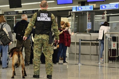 Syryjczycy udawali Greka, Rumuna oraz Marokańczyka funkcjonariusz straży granicznej patroluje port lotniczy. obok funkcjonariusza stoi pies służbowy.