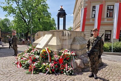 Grób nieznanego żołnierza w Tarnowie na placu ofiar katynia w biało-czerwonych barwach. warte honorowa pełnią żołnierze, pod pomnikiem leża wieńce kwiatów biało-czerwonych
