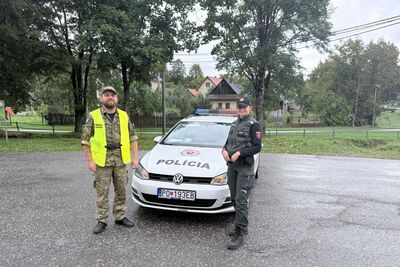 Polski funkcjonariusz w mundurze moro i kamizelce odblaskowej oraz słowacka policjantka stojący przed białym radiowozem słowackiej Policji (VW Golf) w wiejskiej zabudowie.
