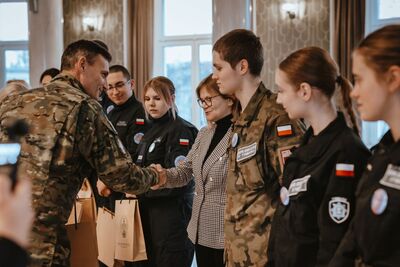 funkcjonariusz sg gratuluje osiągniętego wyniku drużynie z tymbarku, której towarzyszy nauczycielka