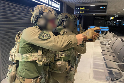 Funkcjonariusze ZIS w oporządzeniu  bojowym z tarczą balistyczna poruszają się na terenie terminala w zwartej grupie szturmowej