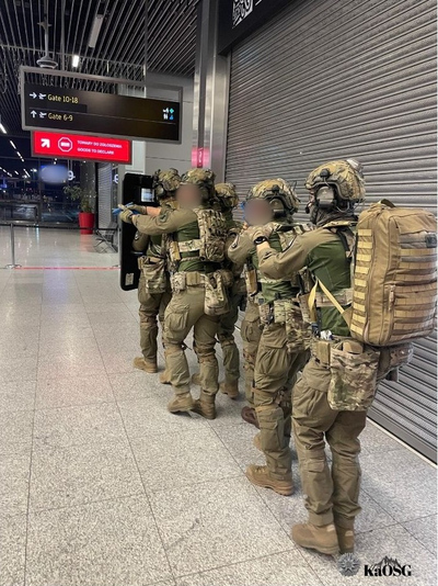 Funkcjonariusze ZIS w oporządzeniu  bojowym z tarczą balistyczna poruszają się na terenie terminala w zwartej grupie szturmowej