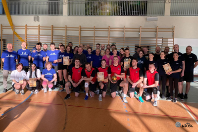 Na zdjęciu widać drużynę sportowcy ubrani w sportowe ciuchy. Zdjęcie zrobione na hali sportowej