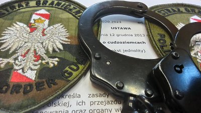 Bójka zakończona deportacją Dwa emblematy Straży Granicznej oraz kajdanki położone na pierwszej stronie ustawy o cudzoziemcach