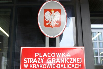 Syryjczycy z (nie)swoimi paszportami godło Rzeczpospolitej polskiej oraz tablica z napisem Placówka Straży Granicznej w Krakowie Balicach