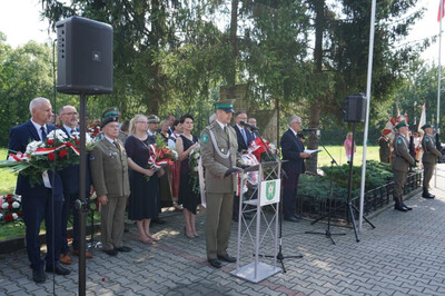 Miejsce uroczystości, plac przed pomnikiem partyzantów, Funkcjonariusz Karpackiego Oddziału Straży Granicznej czyta apel pamięci, w tle uczestnicy uroczystości.