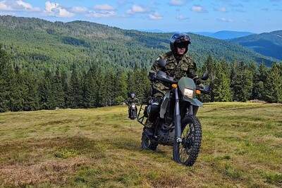 Funkcjonariusze KaOSG współdziałają i pomagają dwóch funkcjonariuszy SG na motocyklach służbowych. patrolują teren gorczańskiego Parku Narodowego. w tle widok na krajobraz Parku