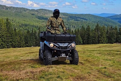 Funkcjonariusze KaOSG współdziałają i pomagają Funkcjonariusz Straży Granicznej poruszający się pojazdem służbowym typu quad patrolujący teren Gorczańskiego parku narodowego. w tle krajobraz na teren parku.