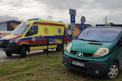 Na parkingu przed supermarketem stoi karetka pogotowia oraz oznakowany bus Straży Granicznej.