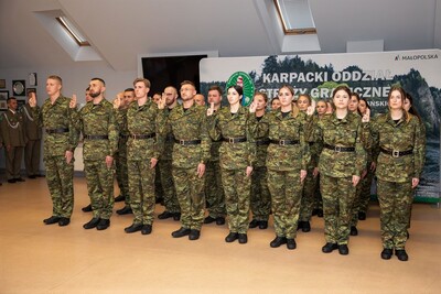 Nowi funkcjonariusze SG ślubowali w obecności Sztandaru KaOSG Sala odpraw. Grupa 30 funkcjonariuszy z podniesionymi do ślubowania dłońmi składa ślubowanie.
