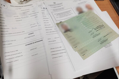 Na biurku leżą dokumenty dot. zatrzymanych cudzoziemców. Są to Tymczasowe Zaświadczenia Tożsamości Cudzoziemca.