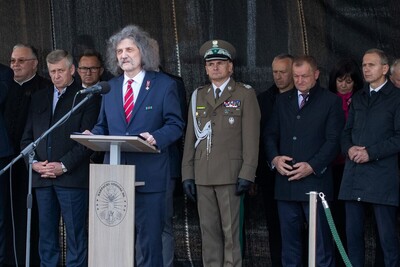 Profesor Jerzy Giza przemawiający do zebranych na uroczystości. Za nim Komendant Karpackiego Oddziału Straży Granicznej oraz zaproszeni goście.