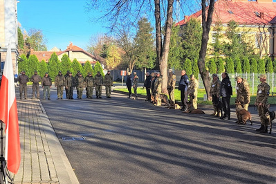 Przed budynkiem stoją ukraińscy przewodnicy psów saperskich, trenerzy psów z Unii Europejskiej oraz psy. W tle stoją funkcjonariusze Straży Granicznej.