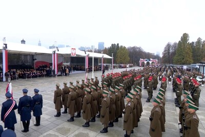 Plac Marszałka Józefa Piłsudskiego w Warszawie. Pod namiotami przedstawiciele najwyższych władz państwowych oraz m.in. Zastępca Komendanta Głównego Straży Granicznej  gen. bryg. SG Wioleta Gorzkowska. Przed trybuną honorową stoją w szyku funkcjonariusze służb mundurowych wśród nich   Kompania Reprezentacyjna Straży Granicznej - która na co dzień wykonuje swoje obowiązki służbowe w Wydziale Odwodowym (Reprezentacyjnym) Karpackiego Oddziału Straży Granicznej. W tle ustrojony w biało-czerwone barwy Grób Nieznanego Żołnierza.