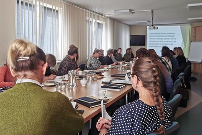 Sala szkoleniowa Powiatowego Urzędu Pracy w Oświęcimiu. Uczestnicy szkolenia  i prelegenci siedzą przy dużym stole konferencyjnym. Na ścianie tablica interaktywna, na której wyświetlany jest slajd dotyczący tematyki szkolenia.
