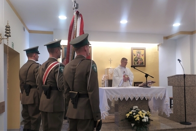 na pierwszym planie poczet sztandarowy ze sztandarem Karpackiego Oddziału Straży Granicznej. Przy ołtarzu kapelan karpackiego oddziału straży granicznej odprawiający mszę świętą.
