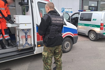 Pomoc w drodze na służbę Funkcjonariusz KaOSG i ratownik medyczny na tle pojazdów służbowych