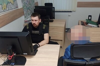 Pomieszczenie biurowe Placówki SG w Tarnowie. Funkcjonariusz siedzi przy biurku przed komputerem. Trwa przesłuchanie zatrzymanego Gruzina. Cudzoziemiec siedzi tyłem przy biurku, ma zapikselizowaną twarz. W tle stoją dwa biurka z położonymi na nich segregatorami i stojącymi na nich monitorami.