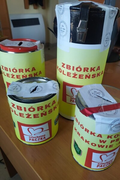 Na biurku stoją cztery zaplombowane puszki z napisem zbiórka koleżeńska szlachetna paczka