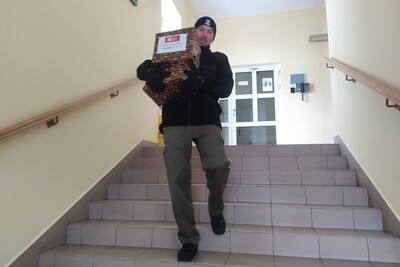 Funkcjonariusz SG idzie w dół  po schodach. Niesie zapakowane w kolorowy ozdobny papier prezenty.