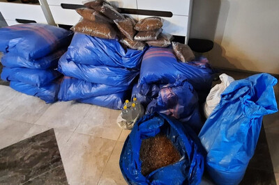 Na podłodze znajduje się kilkanaście dużych niebieskich worków z tytoniem. Na nich leży 9 małych półkiogramowych worki z tytoniem. Obok stoją cztery plastikowe butelki z bezbarwną cieczą.