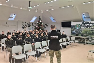 Sala tradycji. Kilkudziesięciu uczniów siedzi na prelekcji, którą wygłasza funkcjonariusz KaOSG.