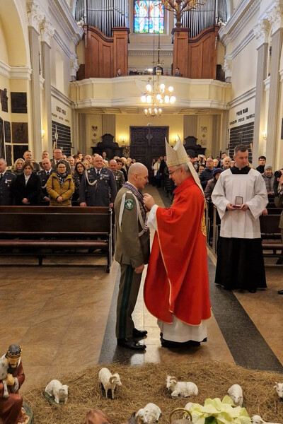 Komendant KaOSG wyróżniony przez Biskupa Polowego Komendant Karpackiego Oddziału Straży Granicznej ma wręczane odznaczenie z rąk Biskupa Polowego. uroczystość odbywa się w kościele.
