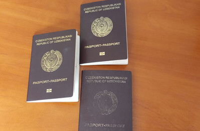 Trzech obywateli Uzbekistanu nielegalnie zatrudnionych w Polsce Trzy paszporty Uzbekistanu położone na drewnianym biurku. Paszporty są koloru czarnego.