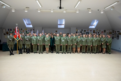 Sala Tradycji karpackiego Oddziału SG. Poczet sztandarowy oraz wszyscy uczestnicy uroczystości pozują w półkolu do pamiątkowego zdjęcia
