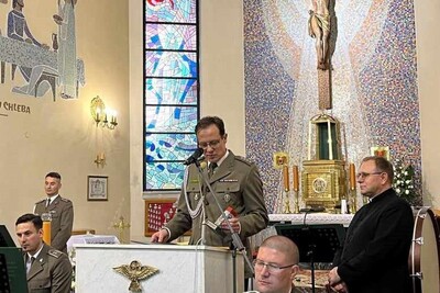 Kościół parafialny Świętego Krzyża i Matki Bożej Nieustającej Pomocy w Tarnowie - Krzyżu. Przy mównicy stoi komendant psg w tarnowie w rękach trzyma statuetkę znaku granicznego koło niego stoi ksiądz proboszcz, przed nim siedzą muzycy orkiestry reprezentacyjnej straży granicznej, w tle ołtarz