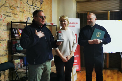 Pomieszczenia domu polskiego w zaporożu. ksiądz, i obdarowane osoby trzymają pamiątki otrzymane od generała laciugi