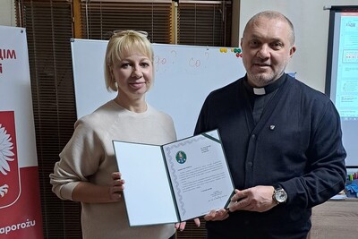 Pomieszczenia domu polskiego w zaporożu. ksiądz, i obdarowana kobieta trzymają pamiątki otrzymane od generała laciugi
