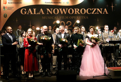 hala sportowa w marcinkowicach. muzycy orkiestry reprezentacyjnej sg grają na gali noworocznej.przed nimi stoją soliści orkiestry trzymajacy bukiety kwiatów w rękach