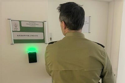 Funkcjonariusz Placówki SG w tarnowie stoi przy drzwiach do miejsca pełnienia służby.