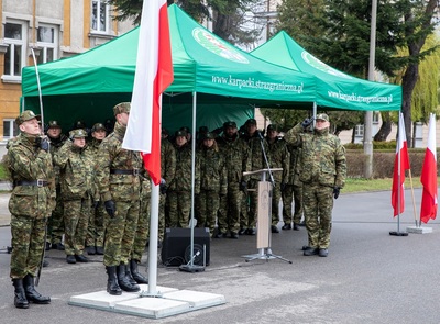 Komendant Karpackiego Oddziału Straży granicznej oddający honor podczas hymnu Narodowego. na drugim planie kadra kierownicza oddziału również oddająca honor podczas hymnu RP.