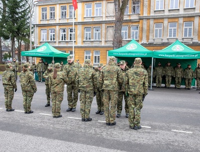 komendant karpackiego oddziału straży granicznej wręczający akty mianowań na pierwszy stopień w korpusie chorążych funkcjonariuszom straży granicznej którzy zakończyli szkolenie.