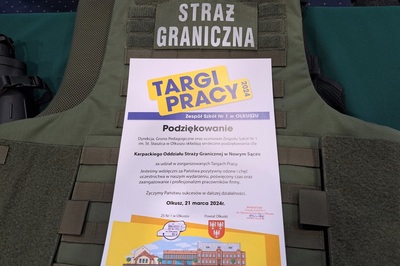 Podziękowanie od organizatorów dla Karpackiego Oddziału Straży granicznej za udział w targach pracy. jest to kartka  formatu a4 położona na stoisku, pod nią znajduje się kamizelka kuloodporna z napisem Straży granicznej.