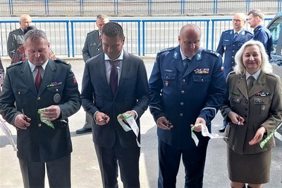 Uczestnicy uroczystości stoją przed budynkiem. Przedstawiciele strony słowackiej i polskiej po przecięciu wstęgi trzymają w rękach nożyczki.