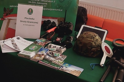 Zachęcali do służby w Straży Granicznej na targach pracy stoisko promocyjne wystawione przez funkcjonariuszy straży granicznej. znajdują się na nim materiały promocyjne, widokówki oraz sprzęt służbowy.