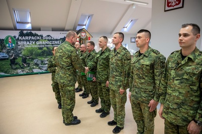 Komendant Karpackiego Oddziału Straży granicznej gratuluje funkcjonariuszom straży granicznej którzy brali udział w zawodach piłki nożnej. komendant dziękuję i gratuluje każdemu z osobna poprzez uścisk dłoni i wręczenie podziękowania w formie papierowej.