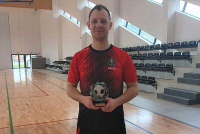 funkcjonariusz straży granicznej, który trzyma statuetkę za najlepszego strzelca turnieju w piłce nożnej. funkcjonariusz ma na sobie strój sportowy .