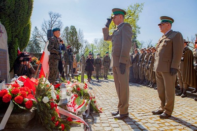 komendant marcisz oddaje honor po złożeniu wieńca pod symbolicznym grobem sybiraków na cmentarzu komunalnym w nowym sączu. przed nim stoi funkcjonariusz który złożył wieniec