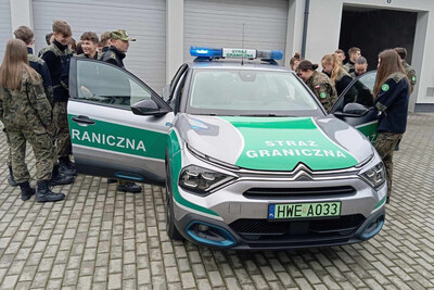 młodzież obserwuje i wchodzi do pojazdu służbowego straży granicznej.