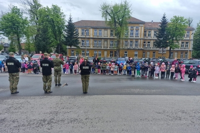 dzieci oglądające pokaz musztry paradnej w wykonaniu  orkiestry reprezentacyjnej straży granicznej.