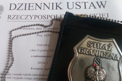 Nepalczyk musi opuścić nasz kraj odznaka straży granicznej wykonana ze stali z napisem straż graniczna i widocznym słupkiem granicznym a na nim widoczny jest orzeł biały , czyli godło Polski. odznaka ułożona jest na wydrukowanej papierowej wersji ustawy o cudzoziemcach.