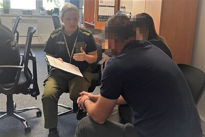 Pomieszczenia placówki sg w krakowie. Zatrzymana Azerka siedzi na krześle, jest przesłuchiwana w obecności tłumacza przez funkcjonariuszkę SG.