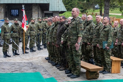 funkcjonariusze Straży Granicznej uczestniczący we mszy świętej. Na pierwszym planie stoi komendant karpackiego oddziału straży granicznej. Za nim stoją inni funkcjonariusze straży granicznej. W tle stoi kompania honorowa straży granicznej ze sztandarem Karpackiego Oddziału straży granicznej.