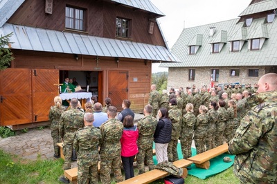 funkcjonariusze Straży Granicznej oraz pracownicy Karpackiego Oddziału straży Granicznej uczestniczący we mszy świętej. W tle kapelan Karpackiego Oddziału straży Granicznej odprawia mszę świętą. W tle stoi kompania honorowa straży granicznej ze sztandarem Karpackiego Oddziału straży granicznej.