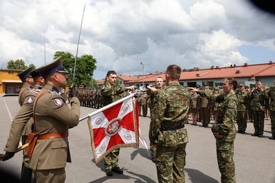 czworo nowo przyjętych funkcjonariuszy straży granicznej ubranych w mundury typu moro ślubują na sztandar Karpackiego oddziału straży granicznej. Stoją przed sztandarem z wyciągniętymi ku niemu prawymi rękami. Dwa palce w dłoni są skierowane ku sztandarowi. Sztandar trzyma funkcjonariusz straży granicznej w asyście dwóch innych funkcjonariuszy. W tle stoja pododdziały zebrane na uroczystości.